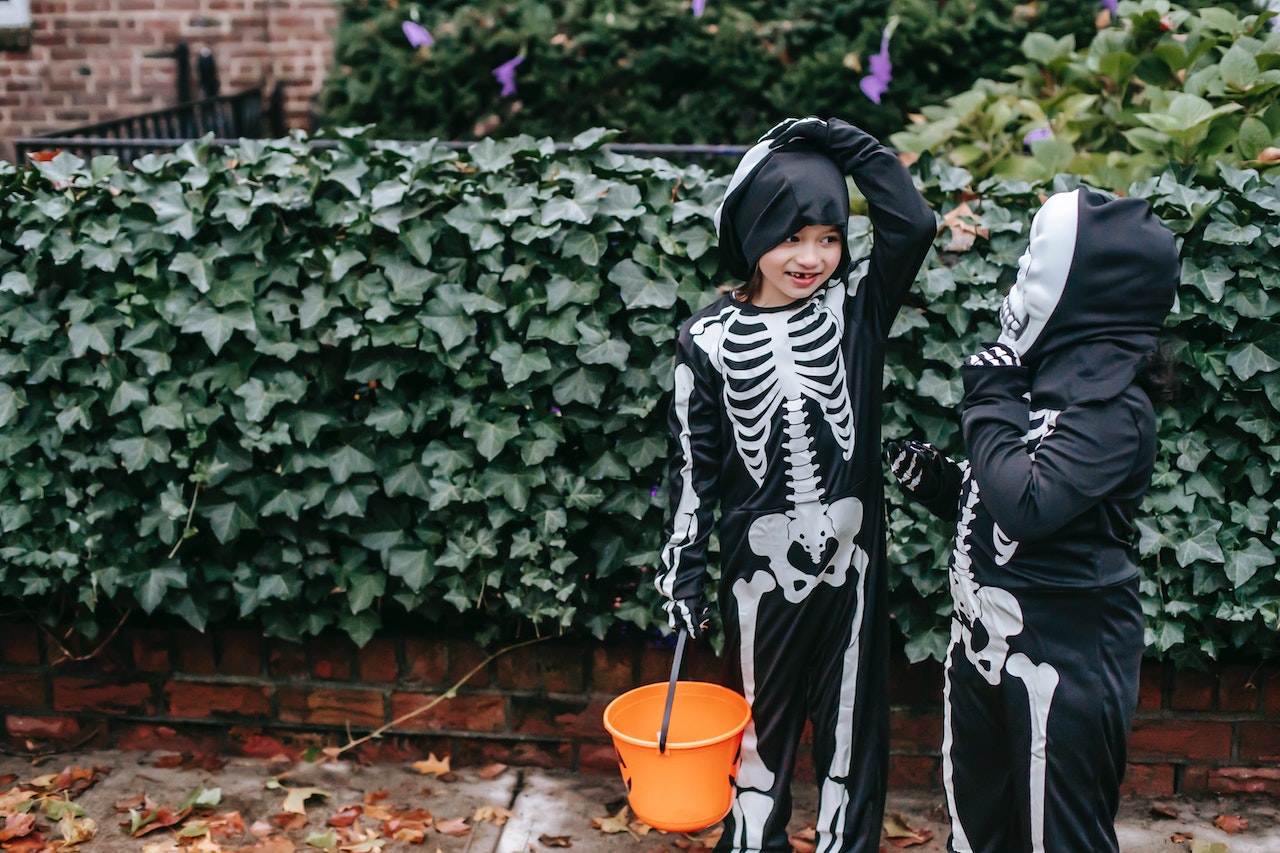 Kids outdoor in skeleton costumes trick-or-treat